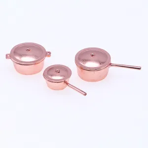 Vue rapprochée détaillée de marmites en métal miniatures pour maison de poupée.