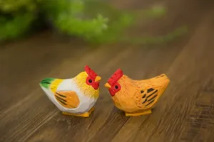Détail de figurines de coq et poule en bois sculpté, idéal pour décoration de bureau et cadeau.