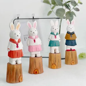 Handcrafted wooden rabbit figurines in cute sailor dresses on tree stump bases. Perfect desktop decor.