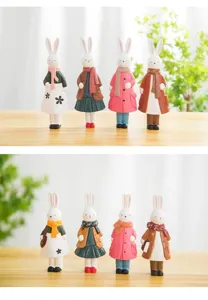 Detailansicht niedlicher Holzkaninchen-Figuren mit bunten Mänteln für Heimdekoration.