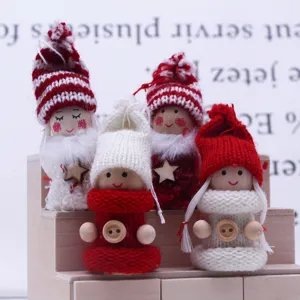 Nahaufnahme von Miniatur-Weihnachtsstrickpuppen auf Holzrequisiten, festive Deko.