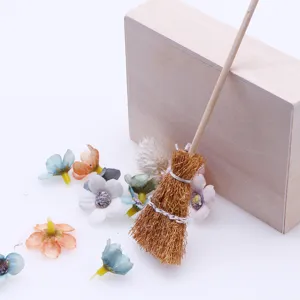 Miniature dollhouse broom model accessory with tiny artificial flowers for DIY craft decor.