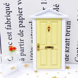 Détail de porte d'entrée de maison de poupée, porte jaune cadre blanc accessoires dorés.