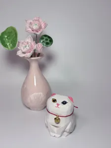 Close-up of a cute handmade wooden cat figurine paired with a ceramic lotus vase detail shot.