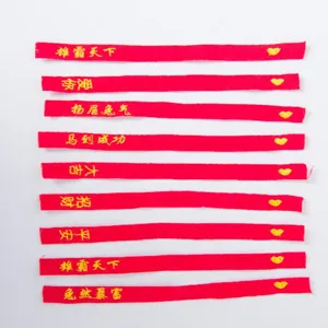 Roter bestickter Stoffstreifen Detail, goldene glückverheißende Schrift und kleines Herz.