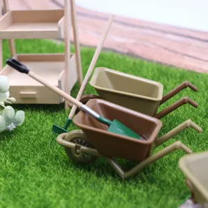 Miniature plastic wheelbarrow and garden tools detail shot for dollhouse landscape decor.