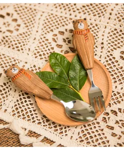 Dettaglio set cucchiaio e forchetta da dessert con manico d'orso in legno, stoviglie carine su piatto.
