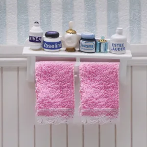 Dollhouse miniature bathroom shelf set featuring pink lace towels and tiny skincare bottles.
