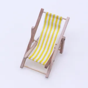 Miniature wooden beach chair detail shot with yellow white striped fabric for dollhouse decor.