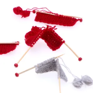 Miniature dollhouse hand knitted sweater model set with tiny wooden needles and yarn.