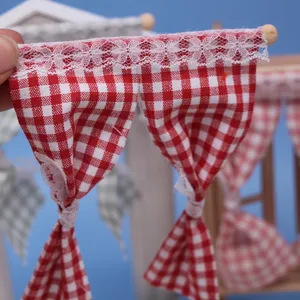 Miniature red and white checkered curtain detail with delicate lace trim for dollhouse decor.