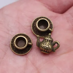 Miniature metal teapot and teacups set, close-up view showing tiny dollhouse scene props.
