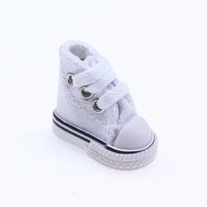 Dettaglio di mini sneaker alta in tela bianca per casa delle bambole e accessori giocattolo