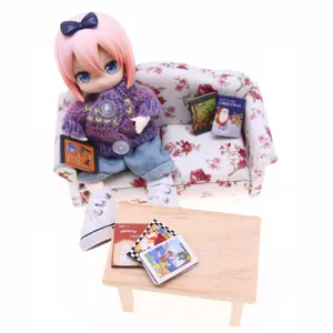 Dollhouse miniature living room scene set with BJD doll, floral sofa, and mini books.