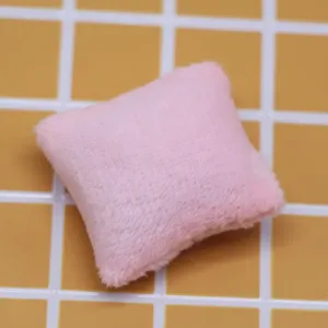 Vue de detail du coussin en peluche rose miniature pour decoration de canape de maison de poupee.
