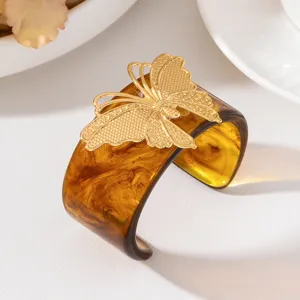 Vista dettagliata del bracciale rigido largo in resina stile europeo con delicata farfalla dorata.