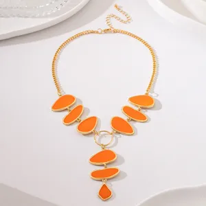Gold statement necklace with vibrant orange enamel oval pendants for elegant party wear.