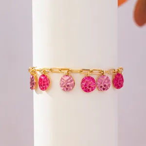 Goldketten-Detail mit leuchtenden rosa strukturierten runden Emailleschmuckanhängern.