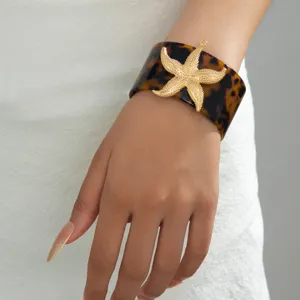 Bracciale largo in resina con dettaglio stella marina dorata, ideale per le vacanze.
