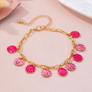 Nahaufnahme Detail der goldfarbenen Kette mit lebendigen rosa strukturierten runden Anhängern.