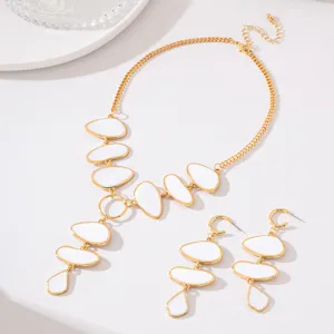Close-up detail of white and gold oval necklace and long earrings jewelry set texture.