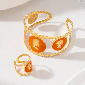 Ensemble bracelet manchette et bague ancienne dorés avec détail émail orange, gros plan.