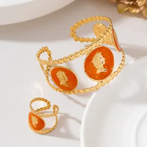 Ensemble de bijoux vintage dorés avec émail orange et design en relief de portrait élégant.