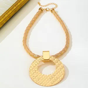 Collier pendentif rond creux texturé de style ethnique doré avec chaîne tressée élégante.