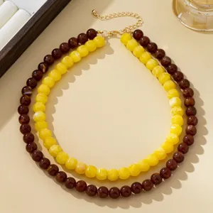 Doppelreihige Perlenkette mit gelben und dunkelbraunen Perlen sowie goldener Kettendetails.