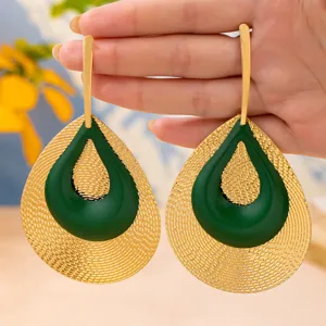 Nahaufnahme von exzentrischen Retro-Ohrringen mit grünem und goldenem Tropfen-Design.