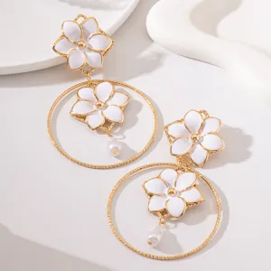 Close-up of retro resort style orange blossom hollow metal ring pearl drop earrings.
