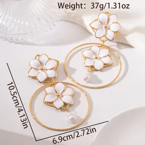 Close-up detail of vintage vacation style white flower metal hoop earrings with pearl pendant.