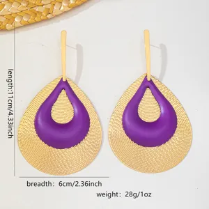 Detailaufnahme retro goldener und violetter tropfenförmiger Ohrringe mit filigranem Design.