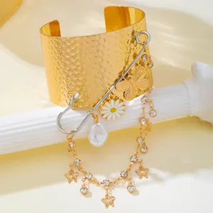 Golden wide cuff bracelet with safety pin charm pendant, detailed closeup shot, sweet cool fashion.