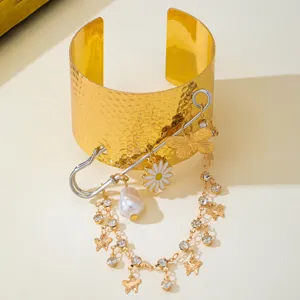 Fashion wide cuff bracelet with safety pin, butterfly, pearl, and rhinestone tassel charms.