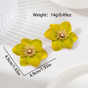 Gros plan détaillé de boucles d'oreilles en métal en forme de fleur aux pétales verts et brillants.