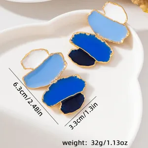 Boucles d'oreilles longues géométriques en émail avec dégradé bleu et élégant bord doré.