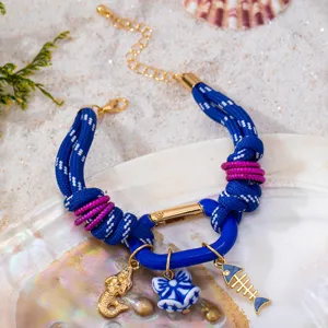 Bracelet tressé bleu style océan avec détails de sirène et breloques en forme d'arête de poisson.