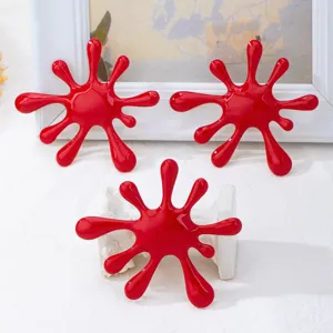 Dettaglio spilla orecchini goccia schizzo rosso, design gioiello vernice irregolare.