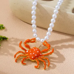 Vista detallada del elegante collar con colgante de cangrejo naranja y perlas blancas.