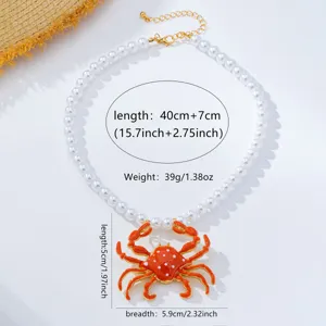 Detalle en primer plano de collar de perlas con colgante de cangrejo naranja y medidas.