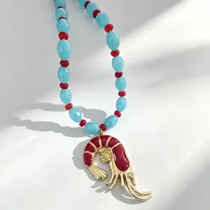 Collar de cuentas de verano con dije de langosta roja, detalle de perlas azules y rojas.