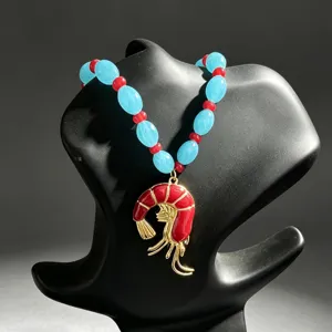 Primer plano de collar de cuentas de colores con un colgante de langosta roja y perlas.