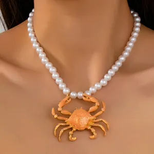 Détail en gros plan d'un collier de perles élégant avec un pendentif crabe doré et émaillé.