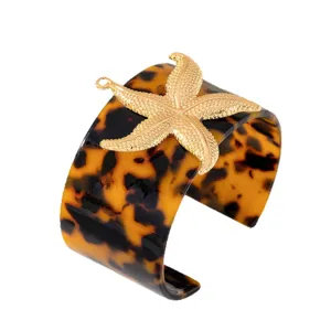 Bracciale rigido largo in resina con dettaglio di stella marina dorata per la moda estiva.