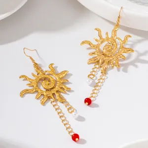Gros plan détaillé de boucles d'oreilles soleil dorées effet martelé avec perles élégantes.