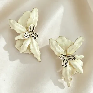 Gros plan détaillé de boucles d'oreilles fleurs blanches à volants avec bords dorés et étamines.
