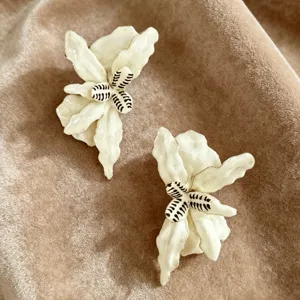 Gros plan de boucles d'oreilles fleurs plissées blanches vintage texture huile velours.