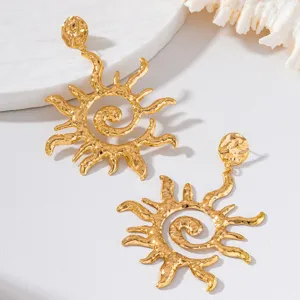 Gros plan de boucles d'oreilles soleil spirale martelées dorées, texture détaillée pour fêtes.