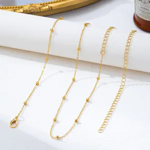 Detailaufnahme der goldenen Metallkette mit Perlen, feine Glieder und Karabinerverschluss.